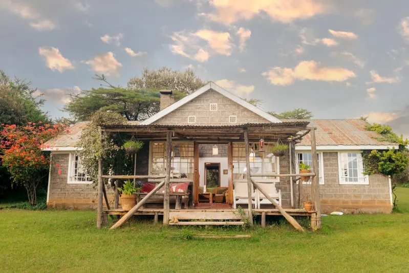 The stone Family Villa with its timber porch, set on a wide lawn among flowering shrubs