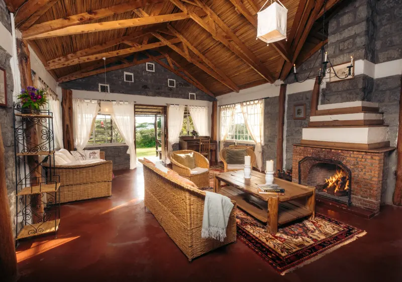 The Family Villa sitting room, wicker sofas around a coffee table before the log fire, under a high timber roof