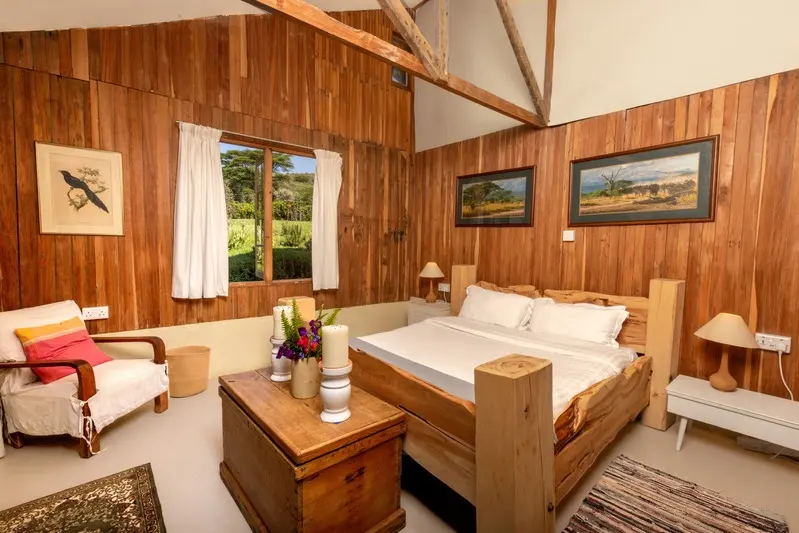The timber-panelled bedroom, the bed made up in white with an armchair by the window
