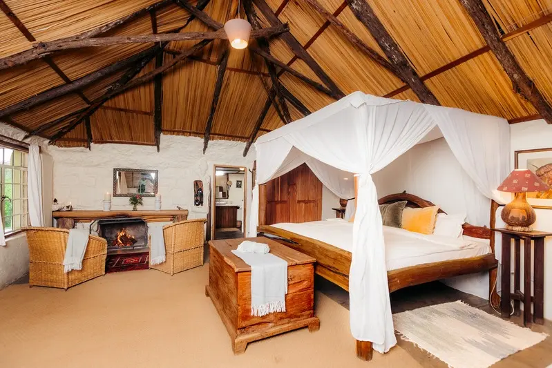 The four-poster bed in the Romantic Cottage, draped in white netting by the fire