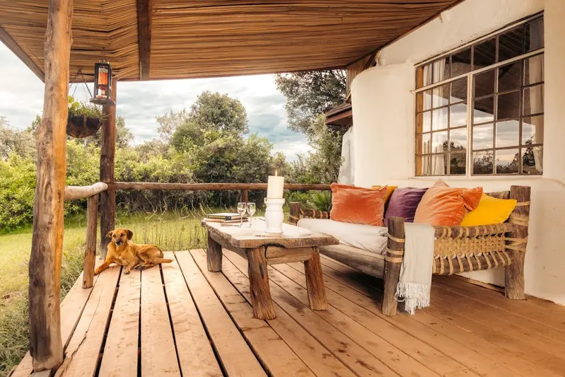 The verandah of the Romantic Cottage, cushions and a daybed looking out to the garden