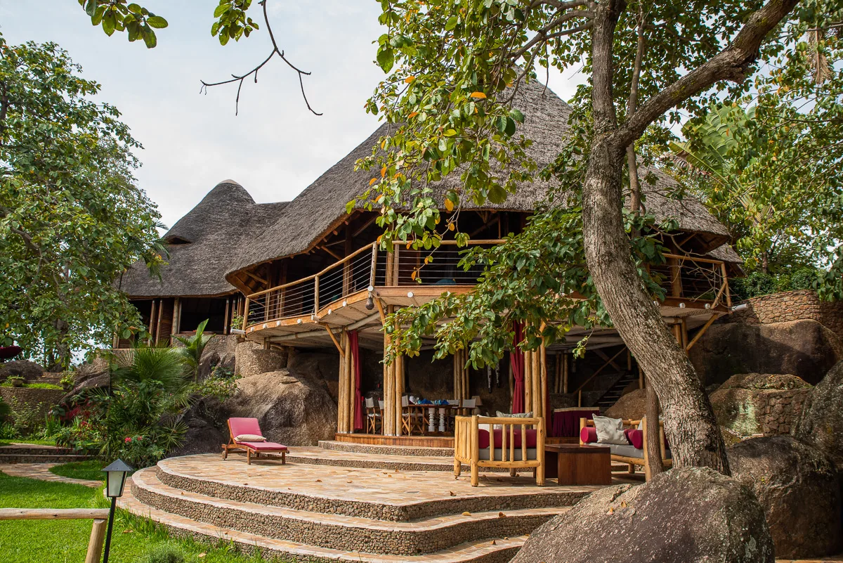A large thatched villa set among granite boulders, with an open upper deck and a shaded lounge below