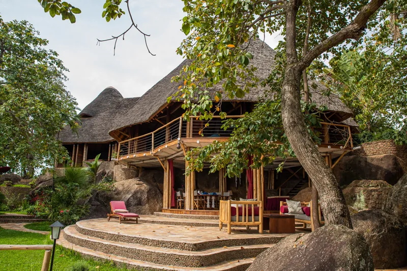 A large thatched villa set among granite boulders, with an open upper deck and a shaded lounge below