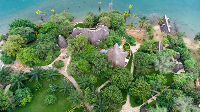 Aerial view of the thatched villas of Sunstone Beach set in tropical gardens along the Lake Tanganyika shoreline