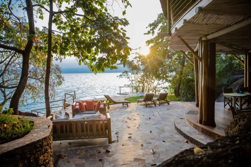 Loungers and a stone terrace looking out over Lake Tanganyika as the sun sets