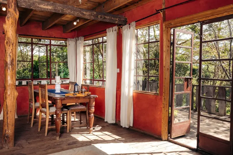 The dining table in a red-walled room, glass doors open onto the deck